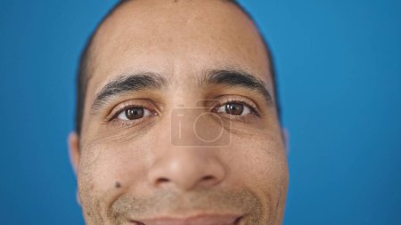 Photo for Young hispanic man close up of eyes smiling over isolated blue background - Royalty Free Image