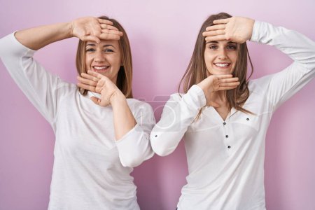 Photo for Middle age mother and young daughter standing over pink background smiling cheerful playing peek a boo with hands showing face. surprised and exited - Royalty Free Image