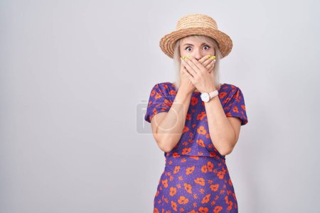 Photo for Young caucasian woman wearing flowers dress and summer hat shocked covering mouth with hands for mistake. secret concept. - Royalty Free Image