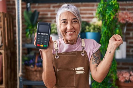Photo for Middle age woman with tattoos working at florist shop holding dataphone screaming proud, celebrating victory and success very excited with raised arm - Royalty Free Image