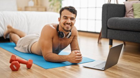 Photo for Young hispanic man smiling confident lying on yoga mat at bedroom - Royalty Free Image