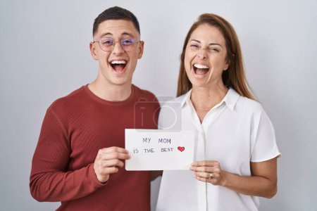 Photo for Mother and son holding my mom is the best card smiling and laughing hard out loud because funny crazy joke. - Royalty Free Image