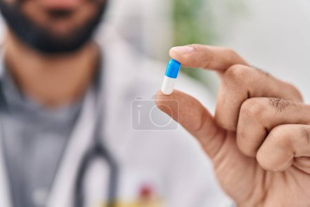 Téléchargez les photos : Jeune homme hispanique médecin tenant la pilule à la clinique - en image libre de droit