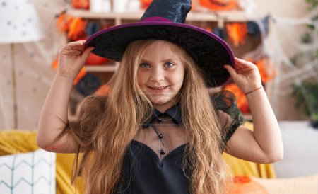 Téléchargez les photos : Adorable fille blonde portant costume de sorcière ayant fête d'Halloween à la maison - en image libre de droit