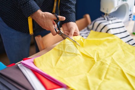Téléchargez les photos : Jeune homme caucasien tailleur tissu de coupe à l'usine de vêtements - en image libre de droit