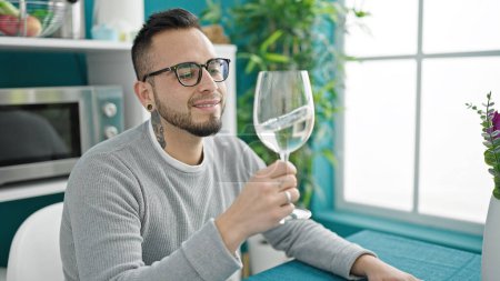 Photo for Hispanic man drinking glass of wine sitting on table at dinning room - Royalty Free Image