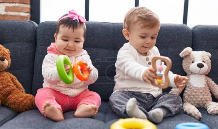 Photo for Adorable boy and girl playing with hoops game sitting on sofa at home - Royalty Free Image