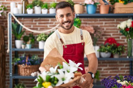 Photo for Young hispanic man florist holding bouquet of flowers at florist - Royalty Free Image