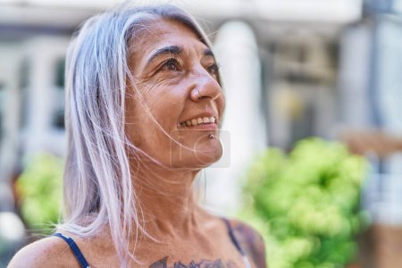 Foto de Middle age grey-haired woman smiling confident looking to the side at street - Imagen libre de derechos