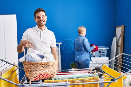 Photo for Hispanic mother and son hanging clothes at clothesline smiling happy pointing with hand and finger - Royalty Free Image