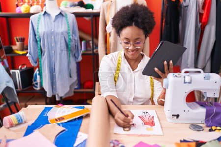 Téléchargez les photos : African american woman tailor using touchpad drawing clothing design at atelier - en image libre de droit