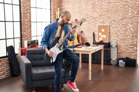 Foto de Joven músico calvo tocando la guitarra eléctrica de pie en el estudio de música - Imagen libre de derechos