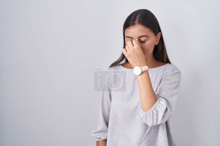 Photo for Young hispanic woman standing over white background tired rubbing nose and eyes feeling fatigue and headache. stress and frustration concept. - Royalty Free Image