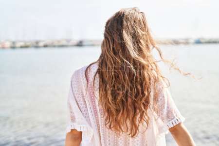 Téléchargez les photos : Jeune belle hispanique femme touriste debout sur la vue arrière à la plage - en image libre de droit