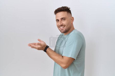 Téléchargez les photos : Homme hispanique avec barbe debout sur fond blanc pointant de côté avec les mains ouvertes paumes montrant l'espace de copie, présentant la publicité souriant heureux heureux - en image libre de droit