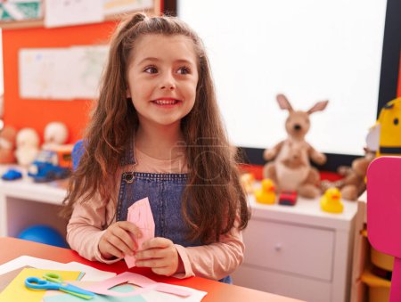 Photo for Adorable hispanic girl smiling confident sitting on table at kindergarten - Royalty Free Image