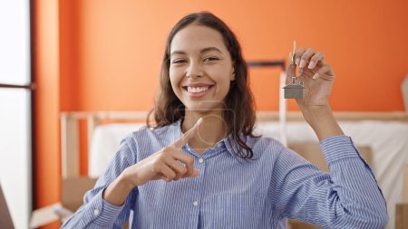 Téléchargez les photos : Jeune belle femme hispanique souriant confiant tenant de nouvelles clés de la maison à la nouvelle maison - en image libre de droit