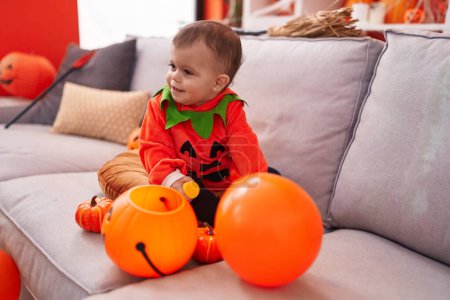 Photo for Adorable hispanic baby having halloween party wearing pumpkin costume at home - Royalty Free Image