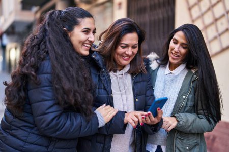 Photo for Three woman mother and daughters using smartphone at street - Royalty Free Image