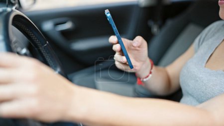 Photo for Young woman using smartphone sitting on car at street - Royalty Free Image