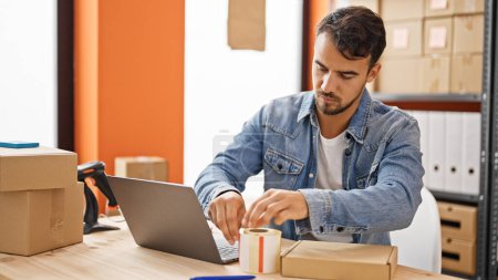 Photo for Young hispanic man ecommerce business worker packing cardboard box at office - Royalty Free Image