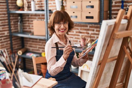 Téléchargez les photos : Femme d'âge moyen artiste souriant dessin confiant à l'atelier d'art - en image libre de droit