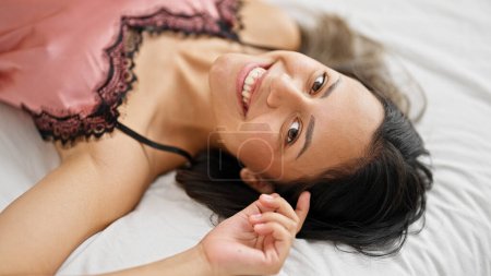 Téléchargez les photos : Jeune belle femme hispanique souriant confiant couché sur le lit dans la chambre - en image libre de droit