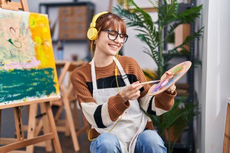 Téléchargez les photos : Jeune femme artiste à l'écoute de dessins musicaux au studio d'art - en image libre de droit