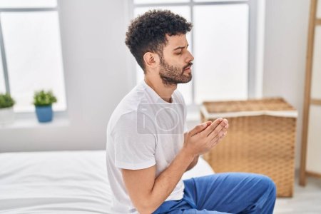Photo for Young arab man praying sitting on bed at bedroom - Royalty Free Image