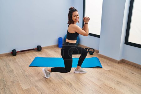 Téléchargez les photos : Jeune belle femme hispanique souriant entraînement confiant jambes exercice au centre sportif - en image libre de droit