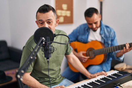 Photo for Two men musicians singing song playing piano and classical guitar at music studio - Royalty Free Image