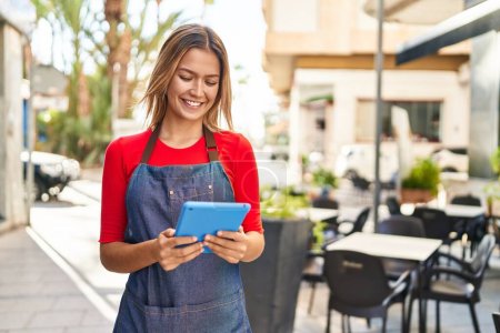 Photo for Young hispanic woman waitress smiling confident using touchpad at coffee shop terrace - Royalty Free Image