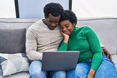 Photo for African american man and woman couple using laptop sitting on sofa at home - Royalty Free Image