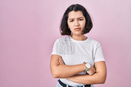 Photo for Young hispanic woman wearing casual white t shirt over pink background skeptic and nervous, disapproving expression on face with crossed arms. negative person. - Royalty Free Image