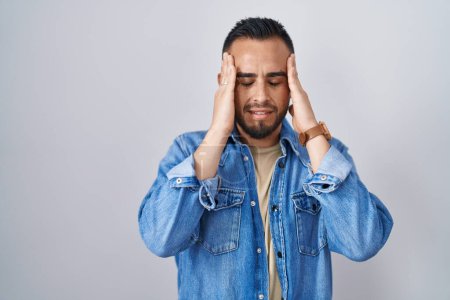 Photo for Young hispanic man standing over isolated background with hand on head, headache because stress. suffering migraine. - Royalty Free Image
