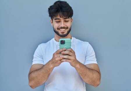 Photo for Young hispanic man smiling confident using smartphone over white isolated background - Royalty Free Image