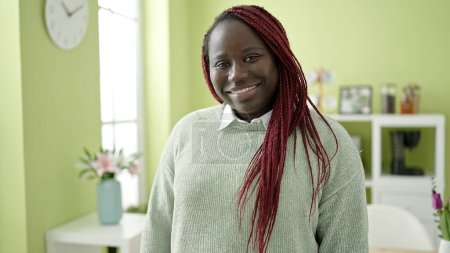 Téléchargez les photos : Femme africaine avec les cheveux tressés souriant confiant à la salle à manger - en image libre de droit