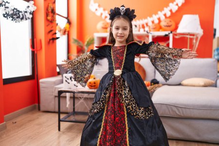 Foto de Adorable chica hispana usando disfraz teniendo fiesta de Halloween en casa - Imagen libre de derechos