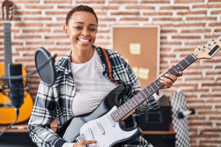 Photo for African american woman musician smiling confident playing electrical guitar at music studio - Royalty Free Image
