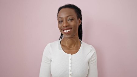 Foto de Mujer afroamericana sonriendo confiada de pie sobre fondo rosa aislado - Imagen libre de derechos