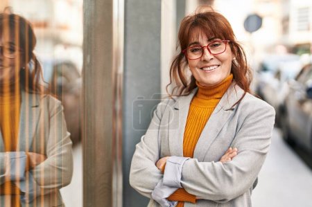 Téléchargez les photos : Middle age woman business executive standing with arms crossed gesture at street - en image libre de droit