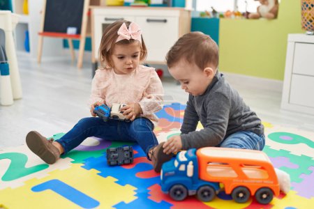 Photo for Adorable boy and girl playing with cars toy sitting on floor at kindergarten - Royalty Free Image
