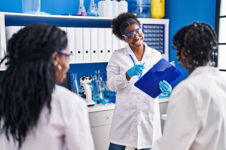 Téléchargez les photos : Amis afro-américains scientifiques expliquant l'expérience au laboratoire - en image libre de droit