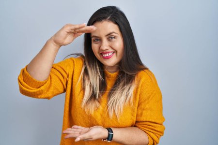 Photo for Young hispanic woman standing over isolated background gesturing with hands showing big and large size sign, measure symbol. smiling looking at the camera. measuring concept. - Royalty Free Image