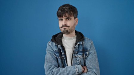 Photo for Young hispanic man standing with upset expression over isolated blue background - Royalty Free Image