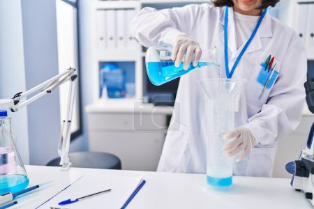 Téléchargez les photos : Jeune femme scientifique versant du liquide sur éprouvette au laboratoire - en image libre de droit