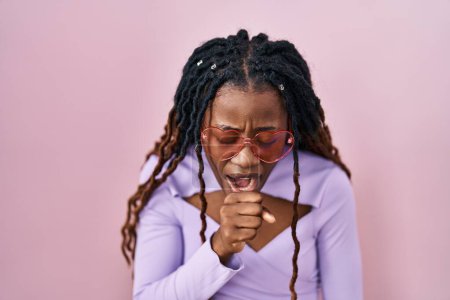 Photo for African woman with braided hair standing over pink background feeling unwell and coughing as symptom for cold or bronchitis. health care concept. - Royalty Free Image