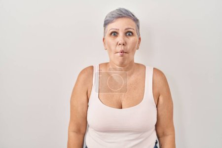 Foto de Middle age caucasian woman standing over white background making fish face with lips, crazy and comical gesture. funny expression. - Imagen libre de derechos