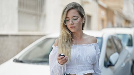 Téléchargez les photos : Jeune femme blonde tenant la clé de la nouvelle voiture à la rue - en image libre de droit