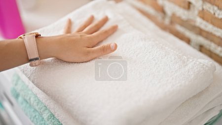 Téléchargez les photos : Jeune belle femme hispanique touchant serviettes pliées à la buanderie - en image libre de droit